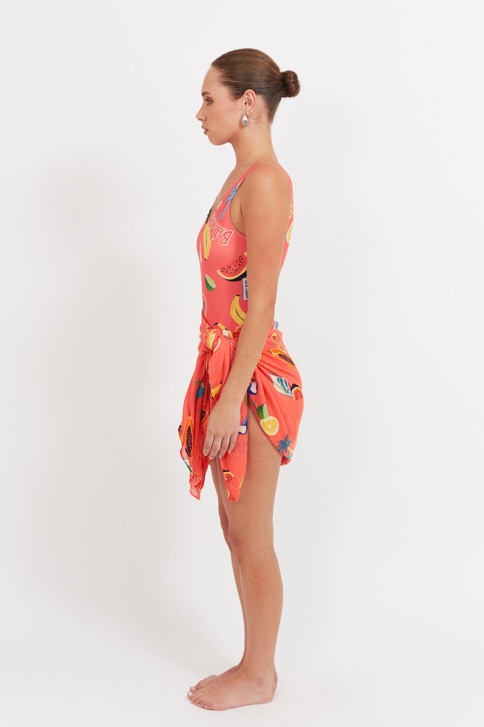 Woman wearing a colorful swimsuit with a matching wrap on a white background