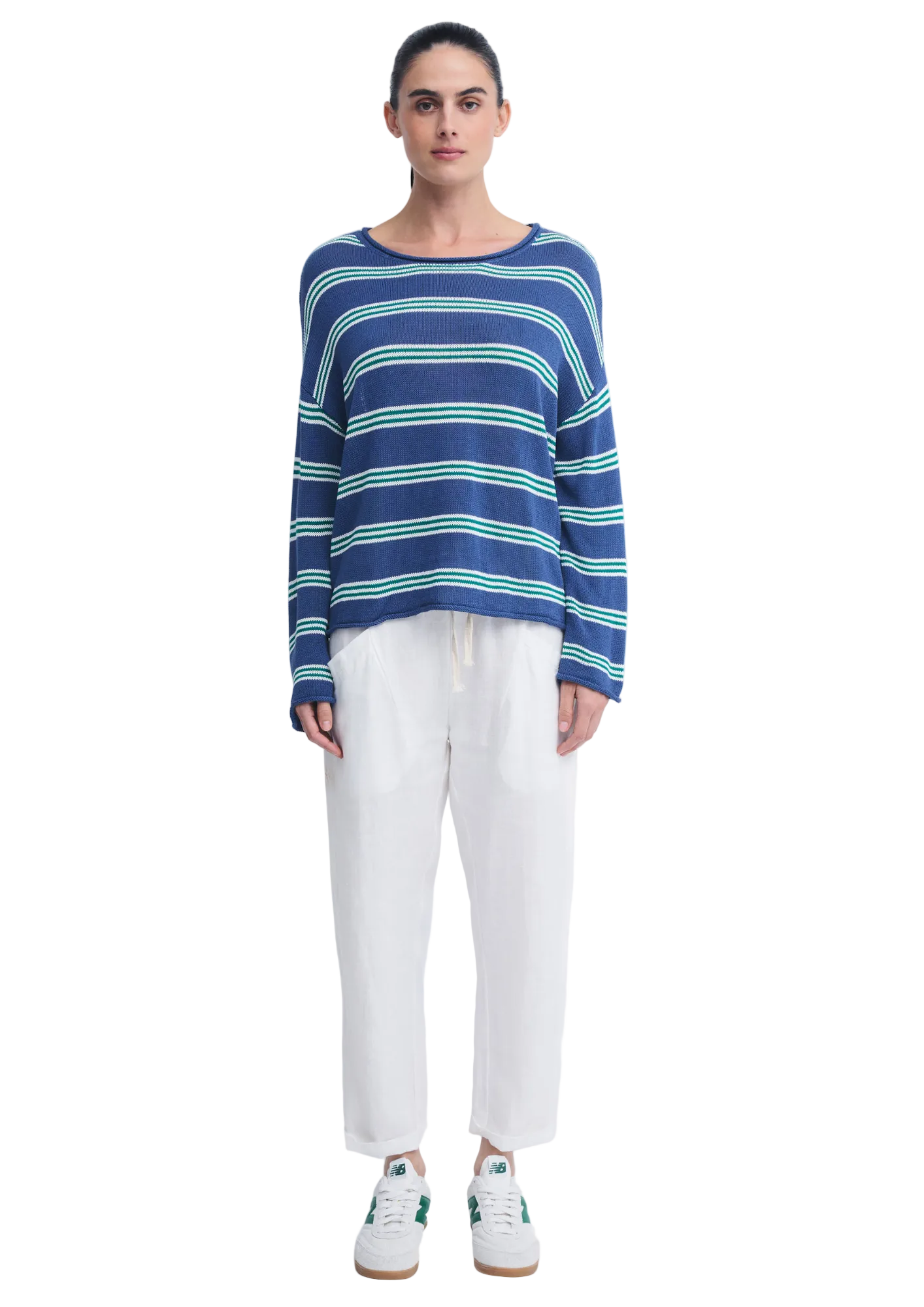 A close-up of a woman wearing a blue knit sweater with horizontal white and green stripes, resting her chin on her hand against a plain light background.